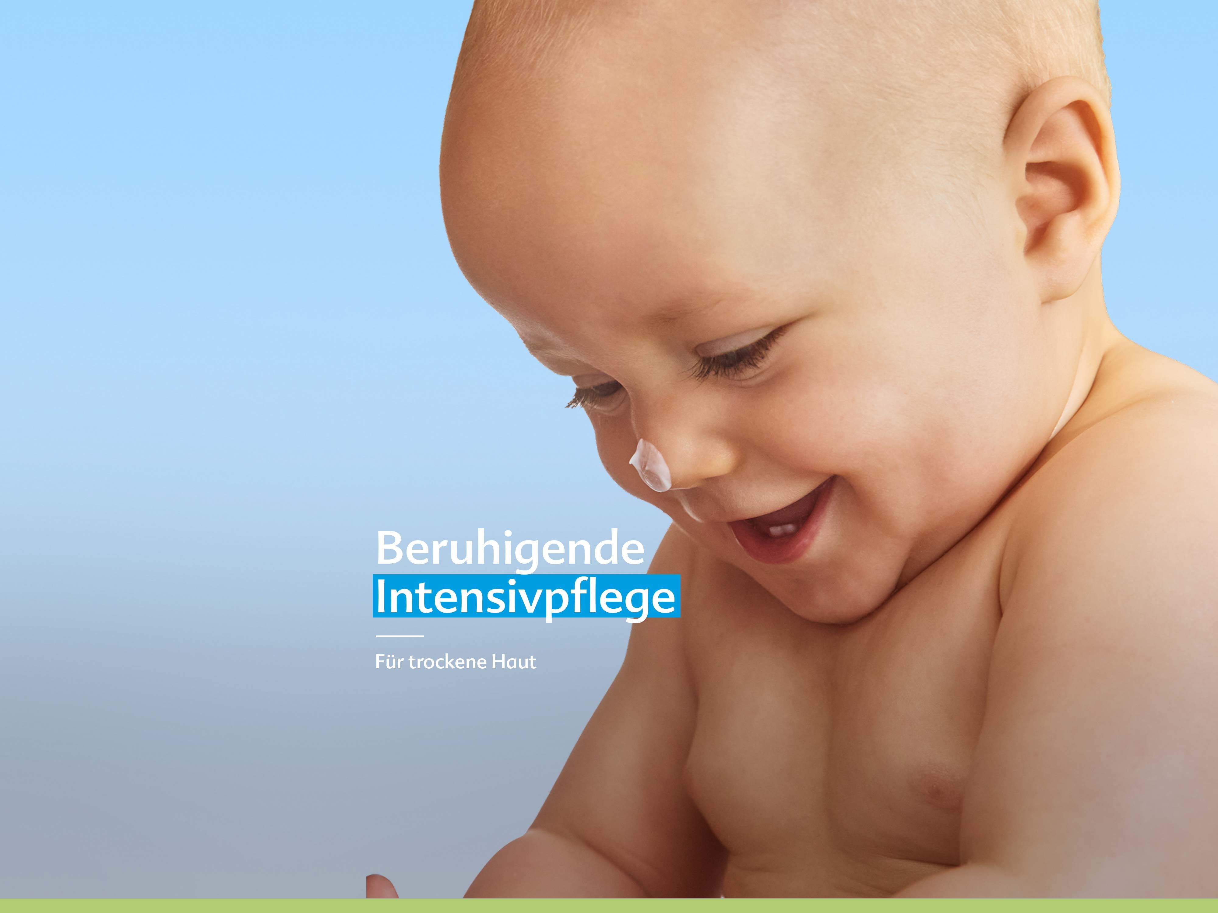 Lachendes Baby mit Creme auf der Nase vor blauem Hintergrund, Text: „Beruhigende Intensivpflege für trockene Haut“