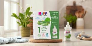 HiPP Organic ready to feed infant starter pack next to a bottle of milk on a kitchen worktop
