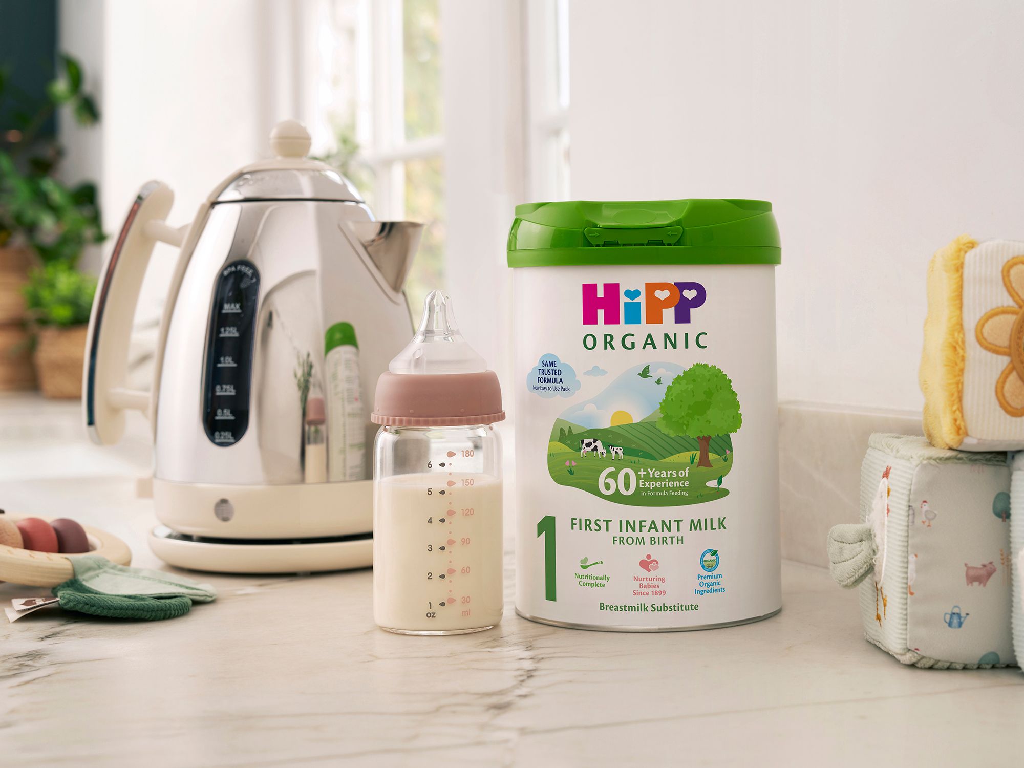 HiPP Organic First Infant Milk Powder Tin on a kitchen worktop next to a bottle of milk