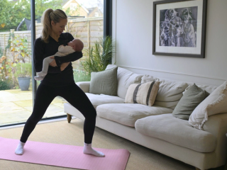 Mum doing gentle stretches whilst holding baby