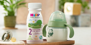 HiPP Organic follow on milk ready to feed bottle next to a beaker on a kitchen worktop