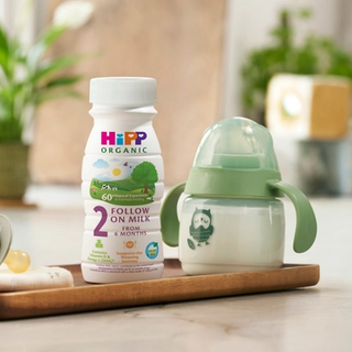 HiPP Organic follow on milk ready to feed bottle next to a beaker on a kitchen worktop
