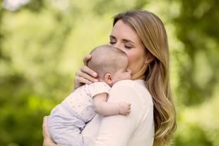 Eine Frau, vermutlich eine Mutter, hält zärtlich ihr Baby und küsst es.