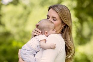 Eine Frau, vermutlich eine Mutter, hält zärtlich ihr Baby und küsst es.
