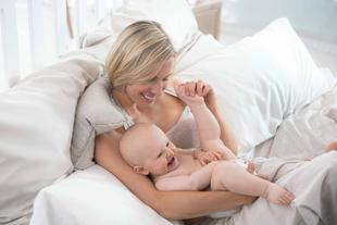 Ein freudiger Moment zwischen einer Mutter und ihrem Baby, in dem die Mutter den Fuß des Babys hält und beide gemeinsam lachen.