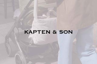 Person schiebt Kinderwagen mit weißer Tasche und schwarzem Schriftzug 'KAPTEN & SON'