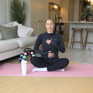 Postnatal mum practicing yoga on a mat in lounge