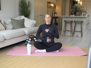 Postnatal mum practicing yoga on a mat in lounge