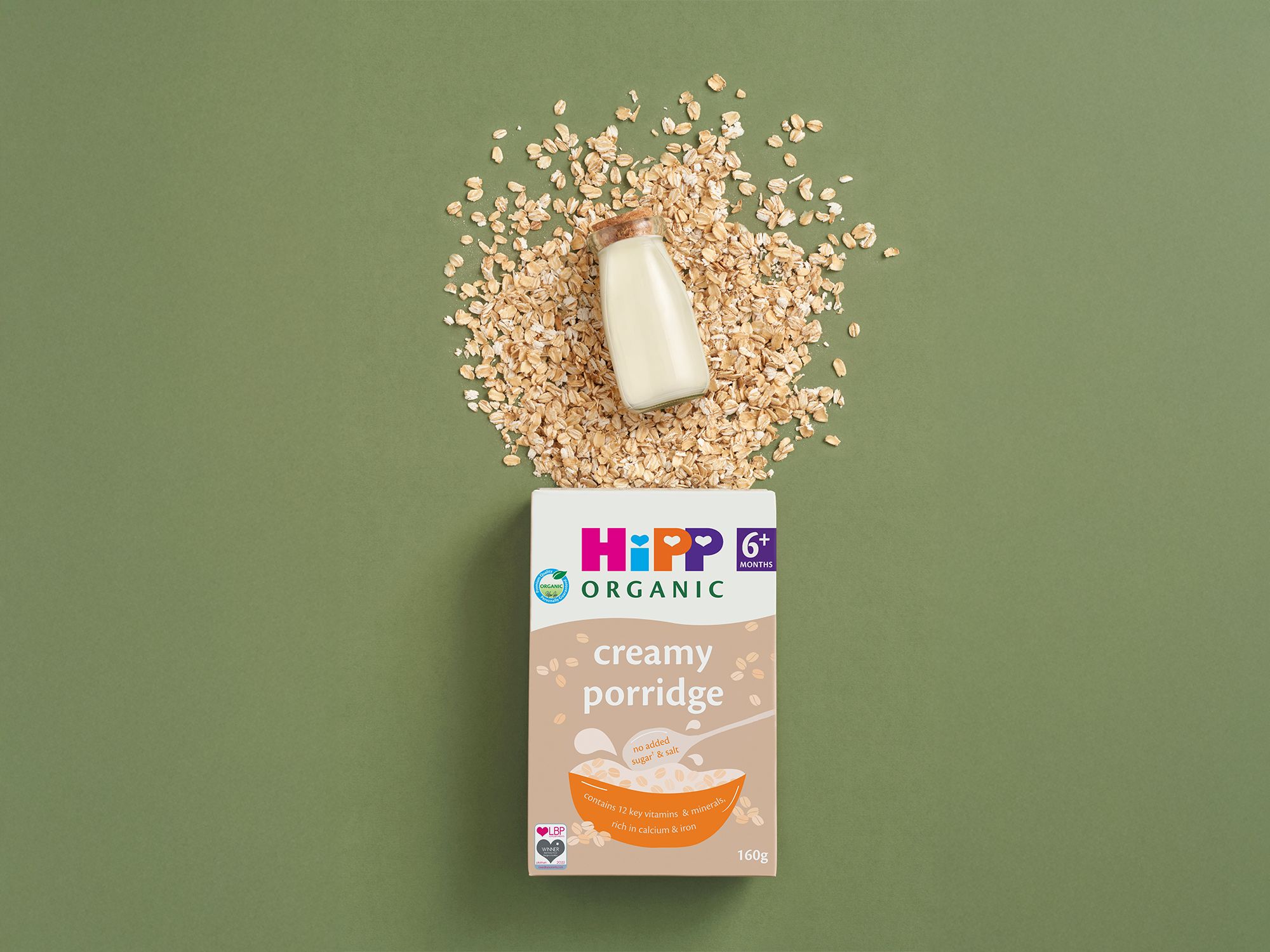 HiPP Organic creamy porridge cereal box with oats and a small milk bottle on a green background