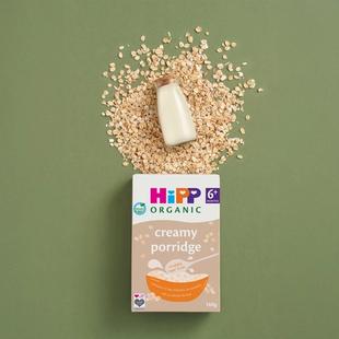 HiPP Organic creamy porridge cereal box with oats and a small milk bottle on a green background