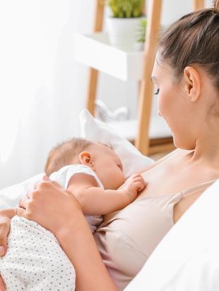 Eine Frau, die ein Baby hält, beide ruhen sich bequem in einer ruhigen Umgebung aus.