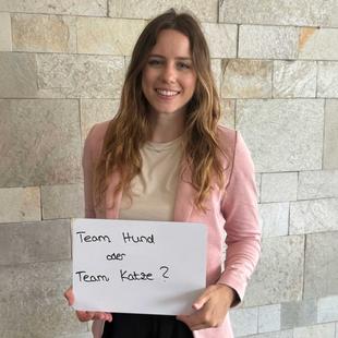 Eine HiPP Mitarbeiterin hält ein Schild 'Team Hund oder Team Katze?'
