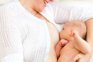 Ein freudiger Moment zwischen einer Mutter und ihrem Baby, wobei die Mutter ihr Kind sanft stillt.