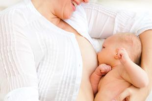 Ein freudiger Moment zwischen einer Mutter und ihrem Baby, wobei die Mutter ihr Kind sanft stillt.