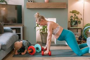 Pregnant mum doing a home workout beside her baby playing on the mat, showing a fun, active Bumps & Burpees moment