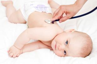 Ein Baby, das auf einer weißen Fläche liegt und ein Stethoskop auf dem Rücken trägt, wobei eine Hand das Stethoskop hält.