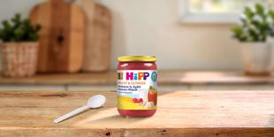 HiPP Bio-Glas Himbeere in Apfel-Bananen-Müesli ab 8 Monaten auf Holztisch mit Löffel in heller Küche