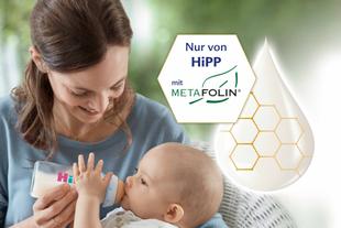 Eine Mutter, die ihr Baby mit einer HiPP-Flasche füttert, begleitet von einem Logo, das auf die Verwendung von Metafolin® hinweist.