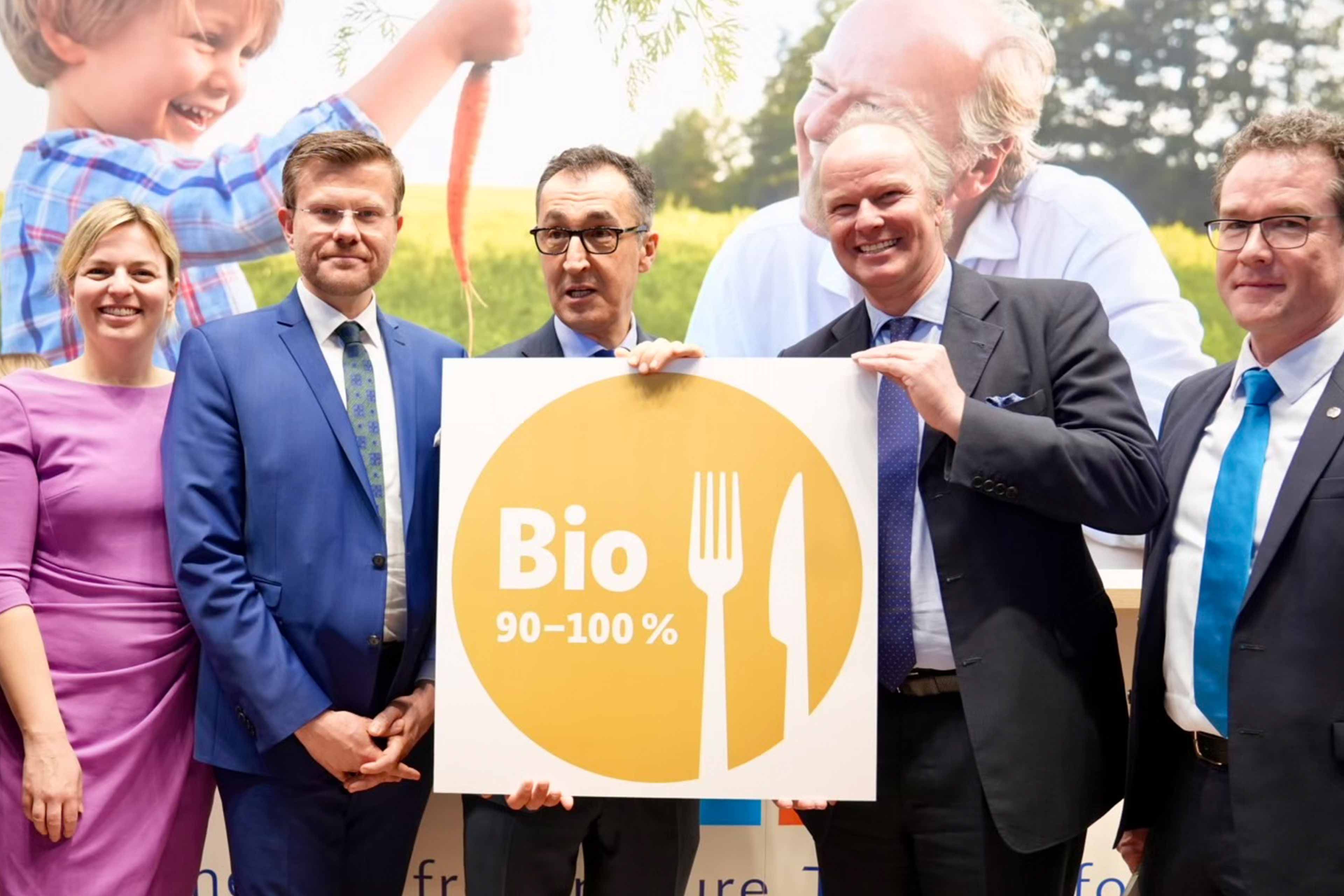 Drei Männer halten ein Schild mit der Aufschrift "Bio 90-100%".