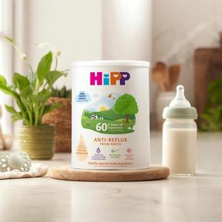 HiPP Organic anti reflux milk powder tin next to milk bottle on a kitchen worktop