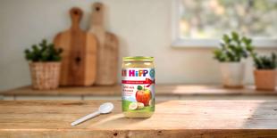 HiPP Bio Fruchtpüree Äpfel mit Bananen 250g im Vorteils-Glas auf Holztisch mit Löffel in heller Küchenumgebung