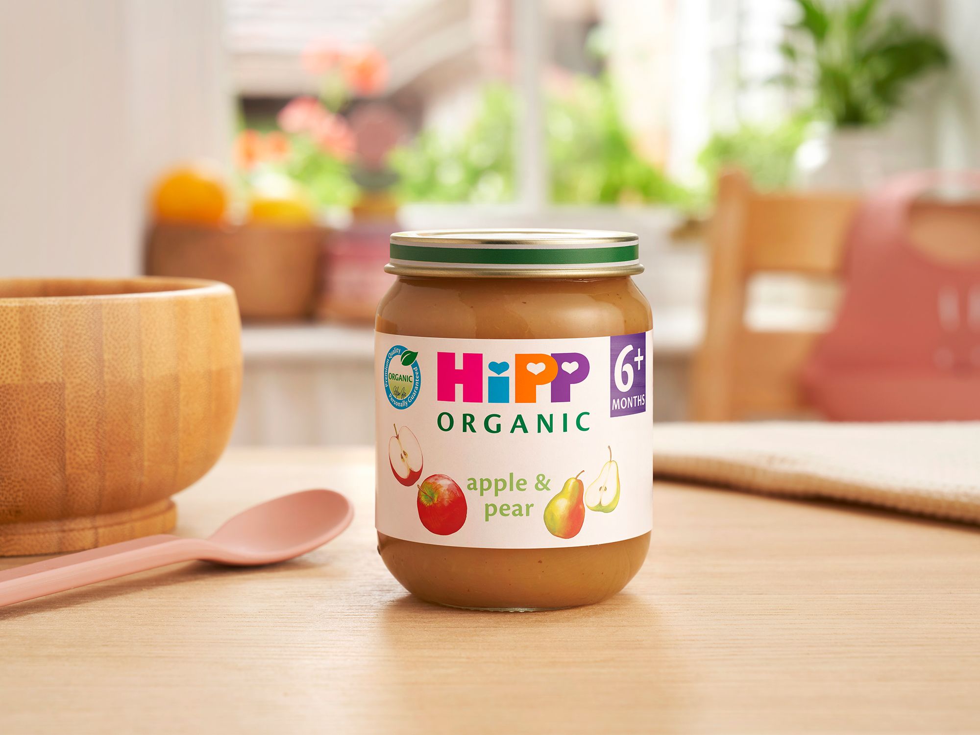 HiPP Organic Apple & Pear jar on a dining table next to a bowl and spoon