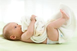 Ein Baby liegt auf dem Rücken und spielt mit einer Kuscheldecke