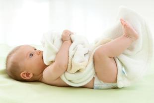 Ein Baby liegt auf dem Rücken und spielt mit einer Kuscheldecke