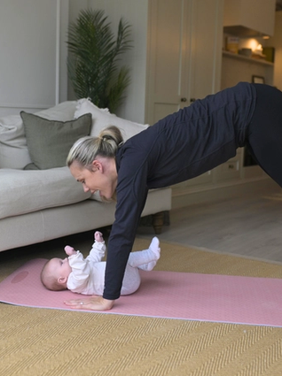 A woman doing a high plank whilst baby lies on mat under her