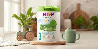 HiPP Organic growing up milk on a kitchen worktop next to a beaker