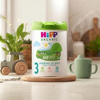 HiPP Organic growing up milk on a kitchen worktop next to a beaker