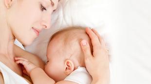 Ein zärtlicher Moment zwischen einer Mutter und ihrem Baby, in dem die Mutter sanft den Kopf des Babys berührt, während das Baby an ihrer Brust ruht.