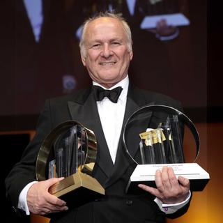 Claus Hipp im schwarzen Anzug mit zwei Awards in der Hand