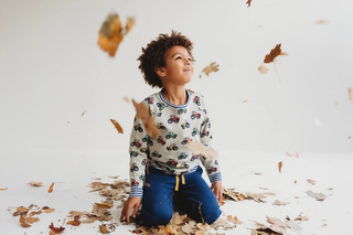 Young boy playing in leaves whilst wearing Lilly + Sid stone tractor top