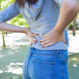 Woman outside holding lower back in pain