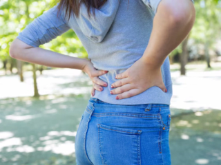 Woman outside holding lower back in pain