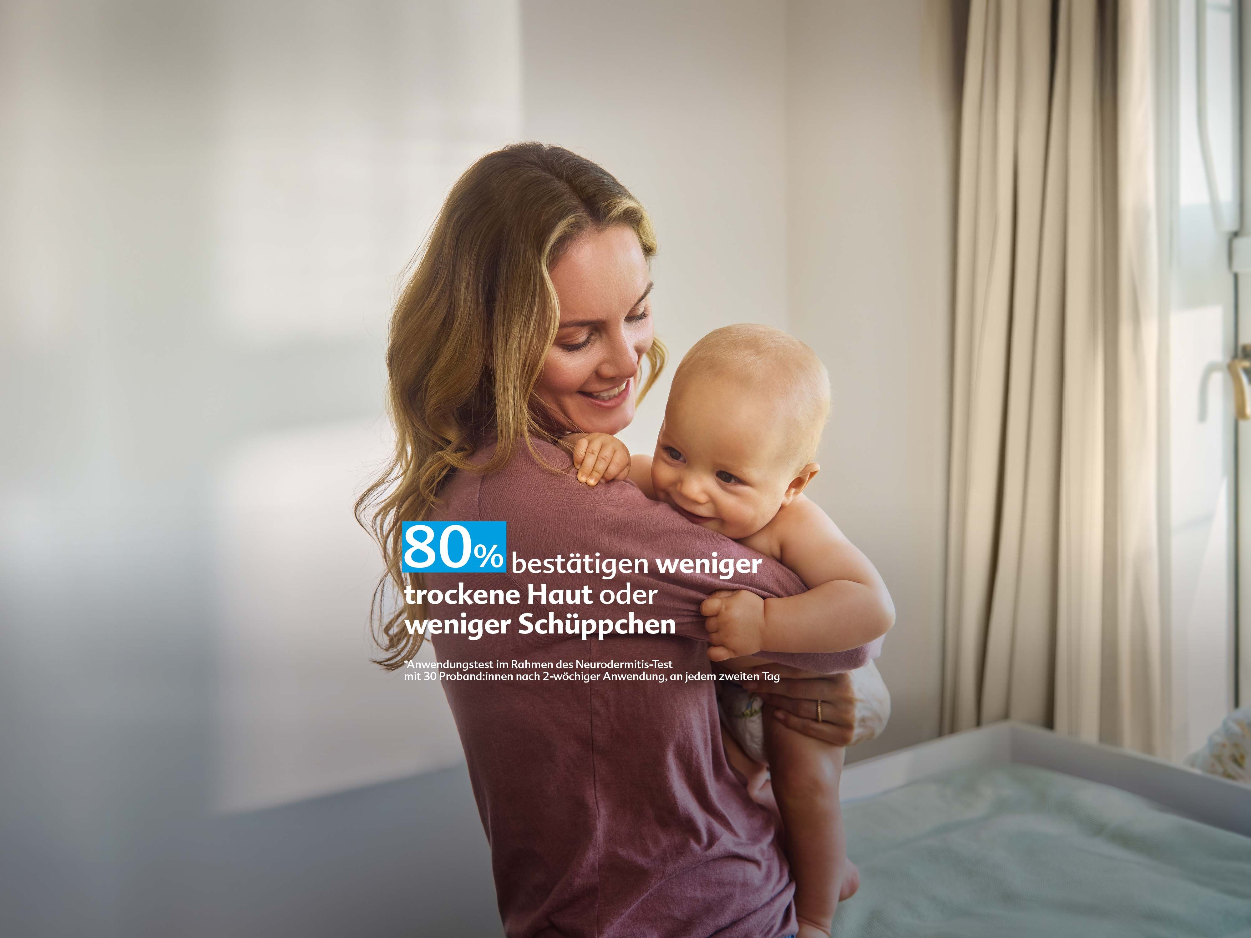 Frau hält lächelnd ein Baby im Arm in einem hellen Raum