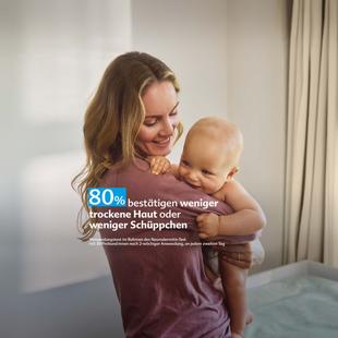 Frau hält lächelnd ein Baby im Arm in einem hellen Raum