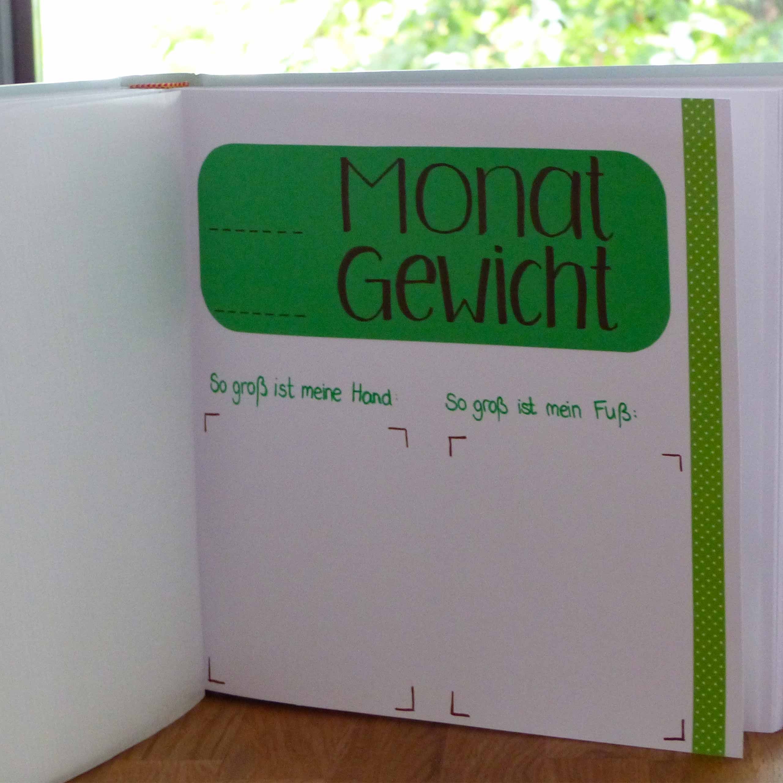 Ein grünes Heftchen mit dem Titel 'Monat Gewicht' mit zwei leeren Abschnitten zum Aufzeichnen des Gewichts, begleitet von einer Wäscheklammer auf der linken Seite.