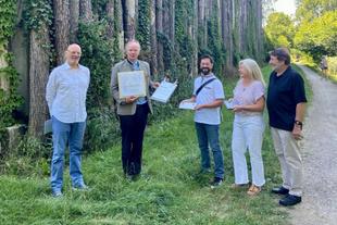 Fünf Personen stehen vor der begrünten Holzfassade des HiPP Parkhauses, überreichen Stefan Hipp im Freien den Bauherrenpreis 2020.