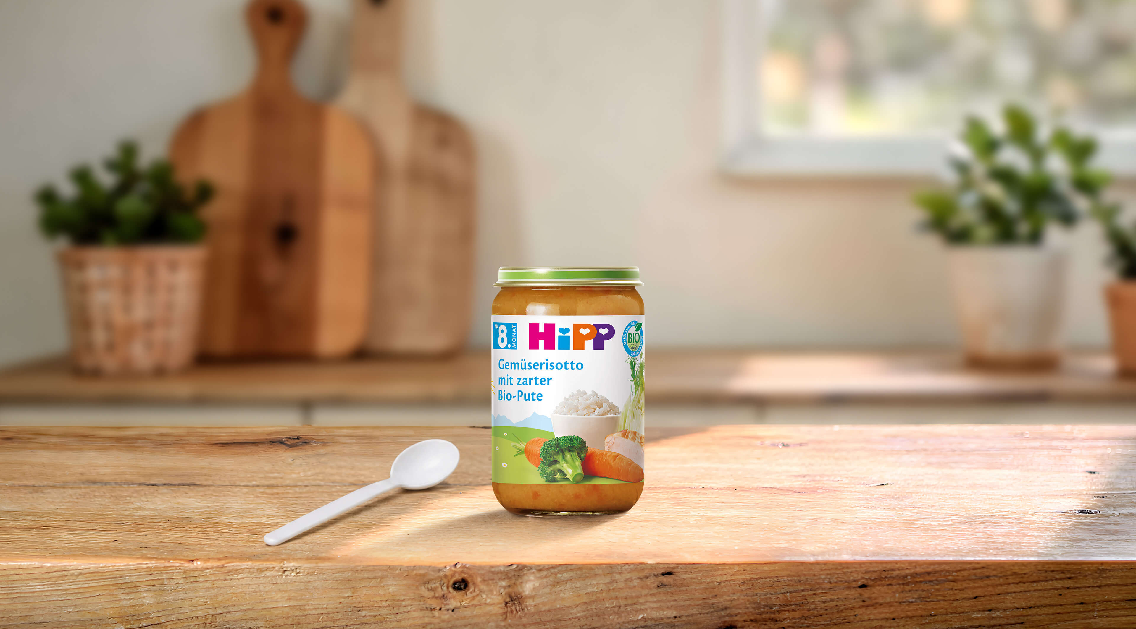 HiPP Gemüserisotto mit zarter Bio-Pute 220g im Glas mit Löffel auf Holztisch in heller, gemütlicher Küche