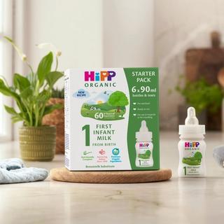 HiPP Organic ready to feed infant starter pack next to a bottle of milk on a kitchen worktop