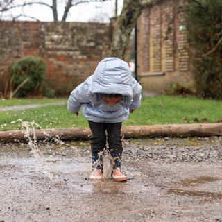 Toddler jumping in puddle