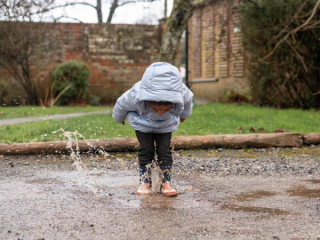 Toddler jumping in puddle