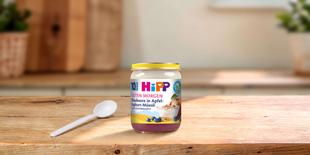 HiPP Guten Morgen Blaubeere in Apfel-Joghurt-Müesli Bio-Babygläschen auf Holztisch mit Löffel in heller Küche