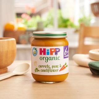 HiPP Organic Carrots, Peas & Cauliflower jar on a dining table next to a bowl and spoon