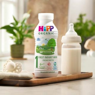First infant milk ready to feed 470ml bottle next to a milk bottle on a kitchen worktop