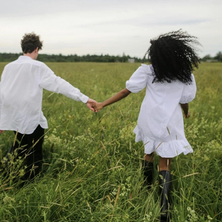 Couple holding hands whilst walking through a field