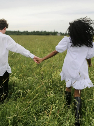 Couple holding hands whilst walking through a field