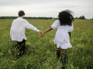 Couple holding hands whilst walking through a field